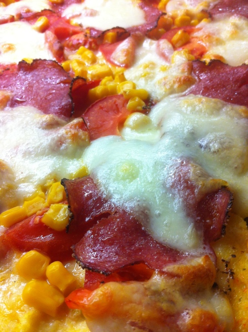 Polenta-Pizza auf dem Blech belegt nach dem Backen